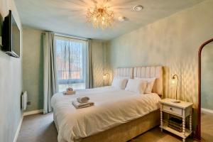 a bedroom with a bed with a chandelier and a window at City Retreat with Parking at Apartment 26 in York