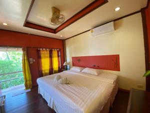 a bedroom with a white bed with a red headboard and a window at Kinnaree Resort Koh Kood in Ko Kood