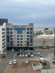 ein Parkplatz mit Autos vor einem großen Gebäude in der Unterkunft Muscat Apartments in Muscat