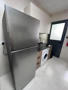 einen Kühlschrank aus Edelstahl in einer Küche mit Waschmaschine in der Unterkunft Muscat Apartments in Muscat