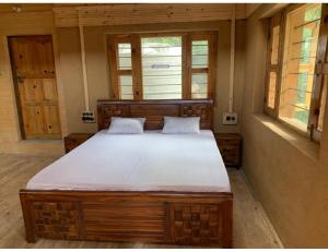 a large bed in a room with two windows at Forest View farmhouse stay, Nainital in Nainital