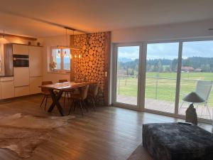 a kitchen and dining room with a table and a large window at Kuh Heimat - Bergblick - Terrasse in Buchenberg