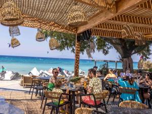 a group of people sitting at tables on the beach at Let it Be Apartments in Theologos