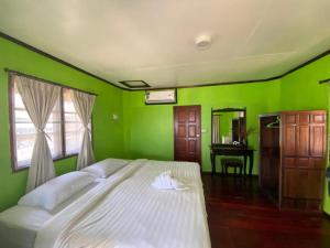 a green bedroom with a white bed and a desk at Kinnaree Resort Koh Kood in Ko Kood