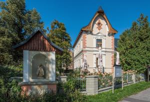 a building with a clock tower next to a fence at Penzion Vila Machů in Kopřivnice