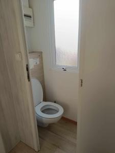 a bathroom with a white toilet with a window at Mobilhome Caraibes in Oye-Plage