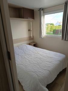 a bedroom with a white bed and a window at Mobilhome Caraibes in Oye-Plage