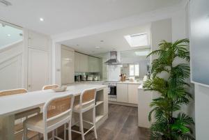 una cocina con armarios blancos y una palmera en el primer plano en GuestReady - Modern Apt in Chelsea with a Terrace, en Londres