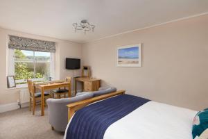 a bedroom with a bed and a desk and a table at Epchris House in Ilfracombe