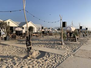una spiaggia sabbiosa con tavoli, ombrelloni e sedie di Het Oude Raadhuis a Noordwijkerhout