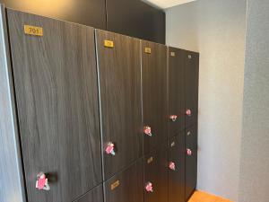 a row of lockers with pink tags on them at カプセルホテル鈴森屋 Capsule Hotel Suzumoriya in Tokyo