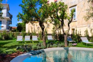 un jardín con sillas y una piscina frente a un edificio en Unconventional Sorrento Coast en Sant'Agnello