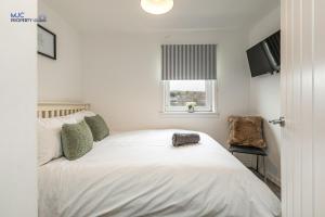 a bedroom with a white bed and a window at Town Centre Apartment in Hawick