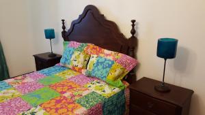 a bed with a colorful quilt and two lamps on tables at Quinta da Lage in Barcelos