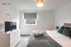 a bedroom with a bed with a flat screen tv at Town Centre Apartment in Hawick