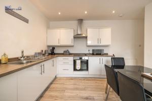 a kitchen with white cabinets and a table with chairs at Town Centre Apartment in Hawick