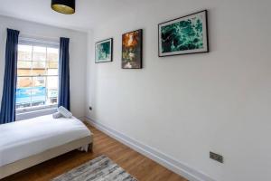 a bedroom with a bed and three paintings on the wall at 1BR Towncenter Serenity - A Coastal Apartment 1 in Christchurch