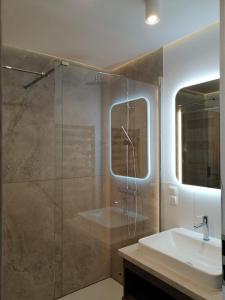 uma casa de banho com uma cabina de duche em vidro e um lavatório. em Rybitwy Residence em Mielno