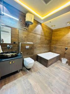 a bathroom with a tub and a toilet and a sink at Taj Ronak Luxury Hotels in Agra