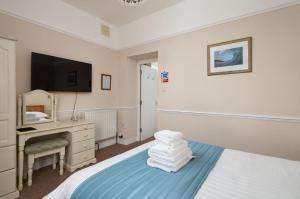 a bedroom with a bed with a desk and a television at Epchris House in Ilfracombe