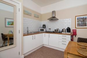 a small kitchen with white cabinets and a table at Epchris House in Ilfracombe