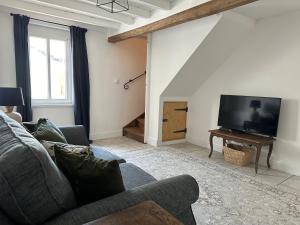 a living room with a couch and a flat screen tv at Charming converted Granary in Capelle-lès Hesdin