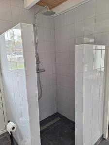 a shower in a bathroom with white tiles at Gastenhuis Amstelmeerzicht. in Westerland