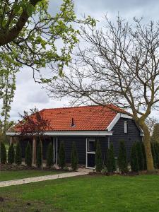 Gastenhuis Amstelmeerzicht. في Westerland: منزل أسود مع سقف برتقالي