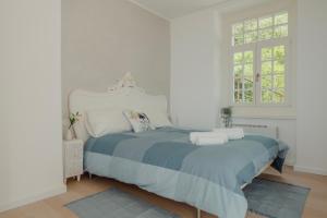 um quarto branco com uma cama grande e lençóis azuis em The sailor's wife house - Santa Croce em Santa Croce Mare