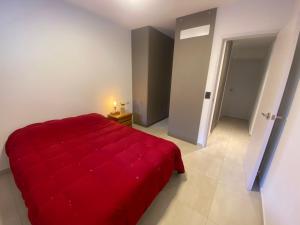 1 dormitorio con 1 cama roja en una habitación blanca en Departamento Rosario en Rosario