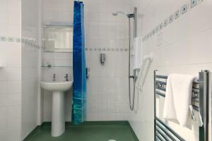 a white bathroom with a sink and a shower at Epchris House in Ilfracombe