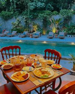 日惹的住宿－Dandaman villa，一张桌子,上面有盘子,放在游泳池边