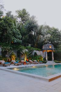 a swimming pool with benches and a gazebo at Dandaman villa in Yogyakarta