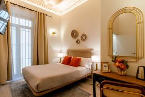 a bedroom with a bed and a mirror and a table at Arco de la Seda - Hotel Boutique in Seville