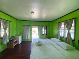 Kinnaree Resort Koh Kood في كو كود: غرفة نوم خضراء بسرير كبير ومخدات بيضاء