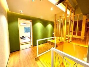 a room with a green wall and a hallway with a staircase at 螢居- 3層100坪別墅 心齋橋道頓堀2站 in Osaka
