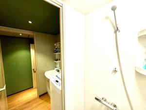 a bathroom with a green wall and a washing machine at 螢居- 3層100坪別墅 心齋橋道頓堀2站 in Osaka