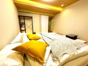 a bedroom with a large bed with yellow pillows at 螢居- 3層100坪別墅 心齋橋道頓堀2站 in Osaka