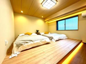 a bedroom with two beds and a window at 螢居- 3層100坪別墅 心齋橋道頓堀2站 in Osaka