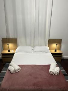 1 dormitorio con 1 cama blanca grande y 2 lámparas en Casa Aconchegante-Rio de janeiro, en Río de Janeiro