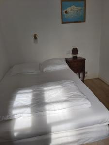 a white bed in a bedroom with a night stand at Maison Quebec in Bernières-sur-Mer