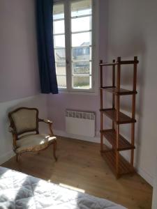 a room with a chair and a book shelf and a window at Maison Quebec in Bernières-sur-Mer