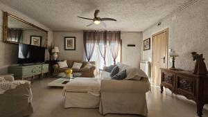 a living room with a couch and a ceiling fan at Villadora Piscina privada & jacuzzi Cerca de la costa brava in Santa Coloma de Farners +35 photos