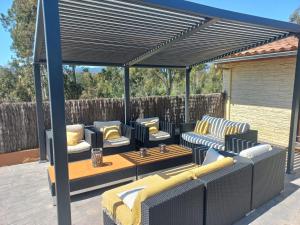 a pergola with couches and tables on a patio at Villadora Piscina privada & jacuzzi Cerca de la costa brava in Santa Coloma de Farners