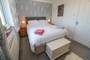 Gwarth An Drae في هيلستون: غرفة نوم صغيرة مع سرير وفوط وردية عليه