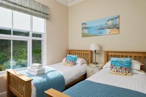 two beds in a room with a window at Epchris House in Ilfracombe