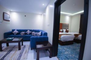 a living room with a blue couch in a hotel room at Loluat Al Matar Furnished Units in Jazan