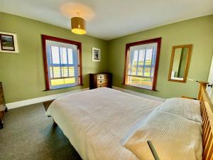 a bedroom with a large bed and three windows at Maytime Cottage in Whitwell
