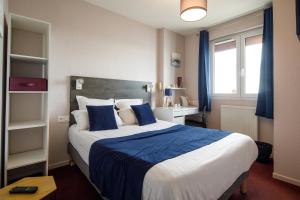 a bedroom with a large bed with blue and white sheets at Saint Aubin Logis Hôtel & Restaurant in Saint-Aubin-sur-Mer