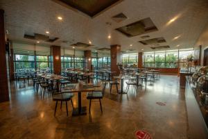 un comedor con mesas, sillas y ventanas en Grand Hotel & Convention Center Karaman, en Karaman